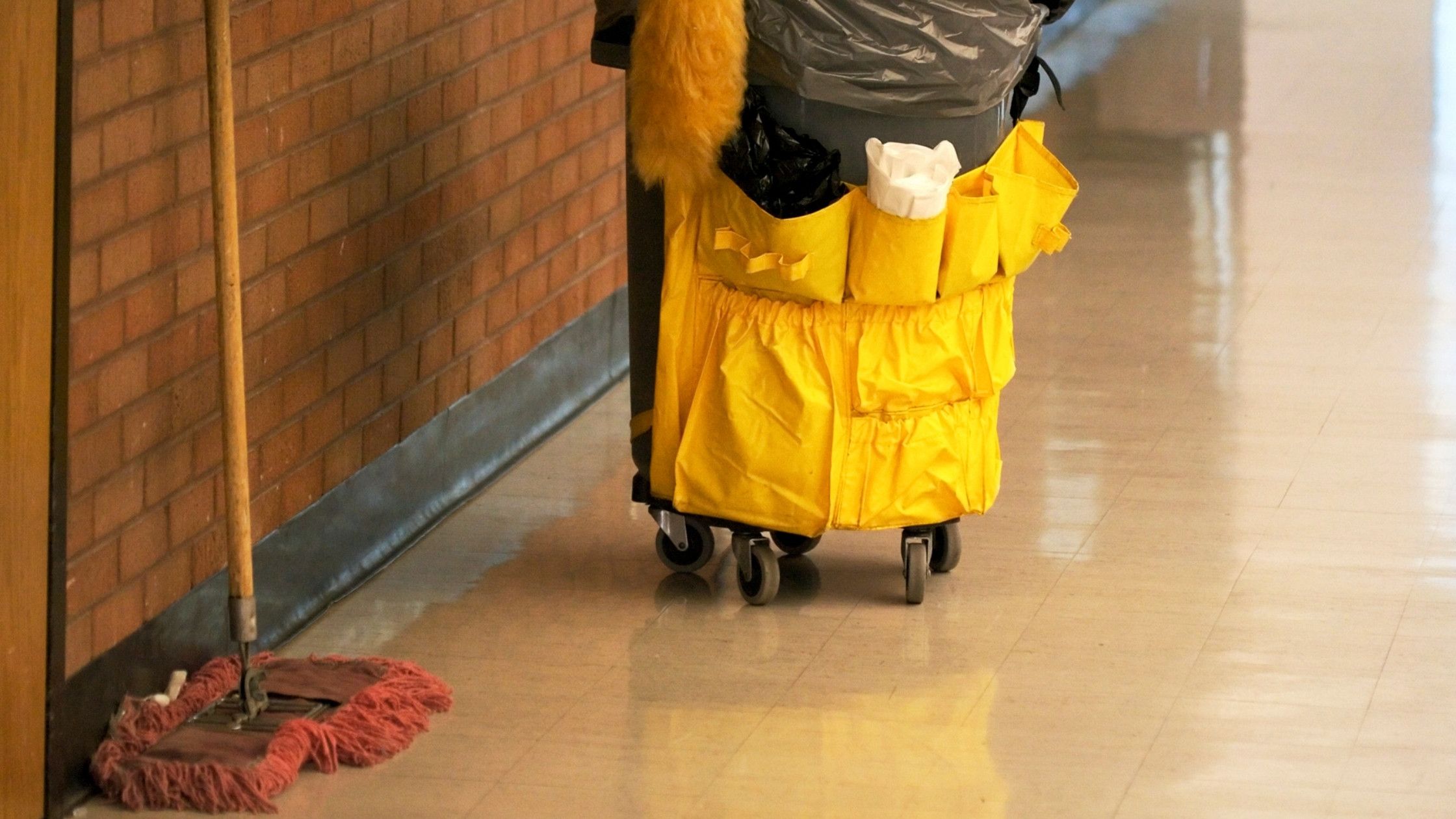 a school hallway with a janitorial cart and a dust mop. empty